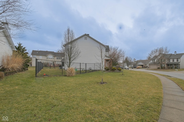 view of property exterior featuring fence, a lawn, and a residential view