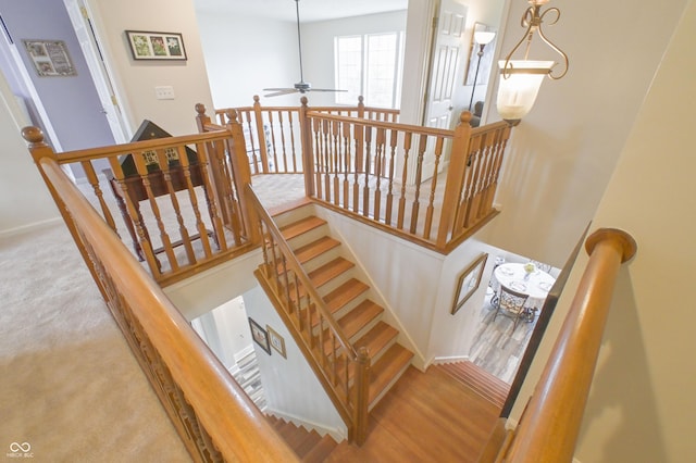 stairs with wood finished floors and a ceiling fan