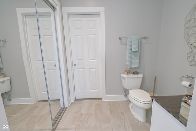 bathroom with toilet, a closet, and baseboards