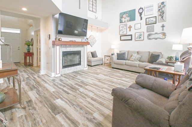 living room featuring a tile fireplace, wood finished floors, recessed lighting, and baseboards
