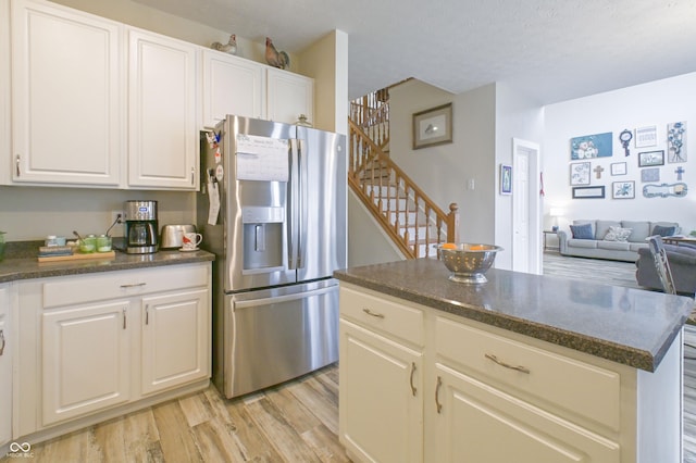 kitchen with white cabinetry, a center island, stainless steel fridge, and light wood-style floors