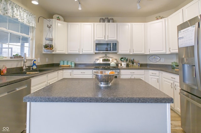 kitchen with appliances with stainless steel finishes, dark countertops, track lighting, and a sink