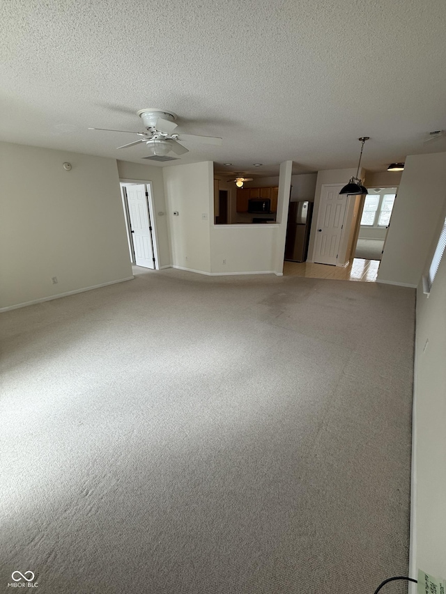 unfurnished living room with ceiling fan, carpet, and a textured ceiling