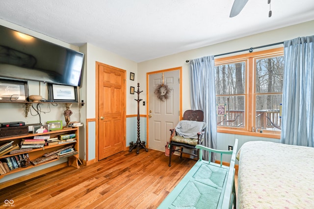 bedroom with light wood-style floors, a textured ceiling, and a ceiling fan