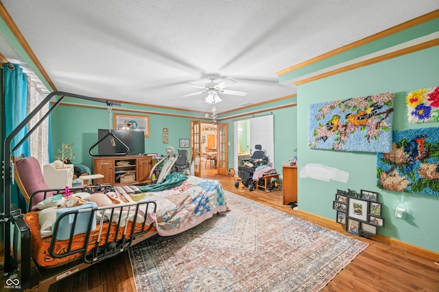 bedroom featuring baseboards, a ceiling fan, wood finished floors, a textured ceiling, and crown molding