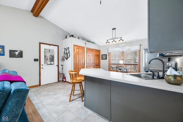 kitchen with lofted ceiling with beams, gray cabinetry, a sink, light countertops, and pendant lighting