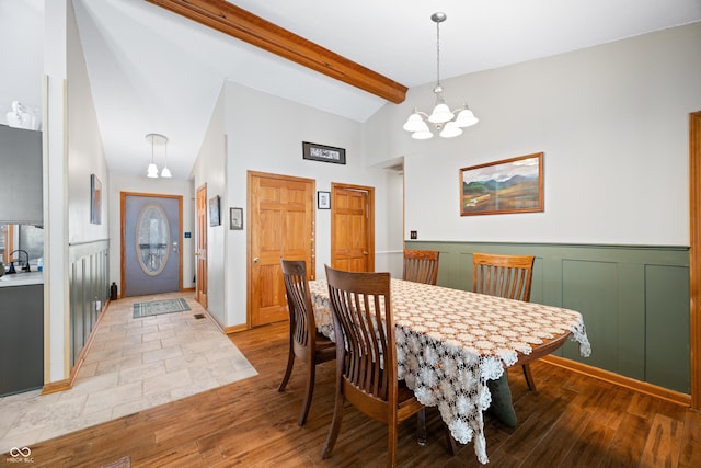 dining space featuring a chandelier, high vaulted ceiling, wainscoting, light wood-type flooring, and beamed ceiling