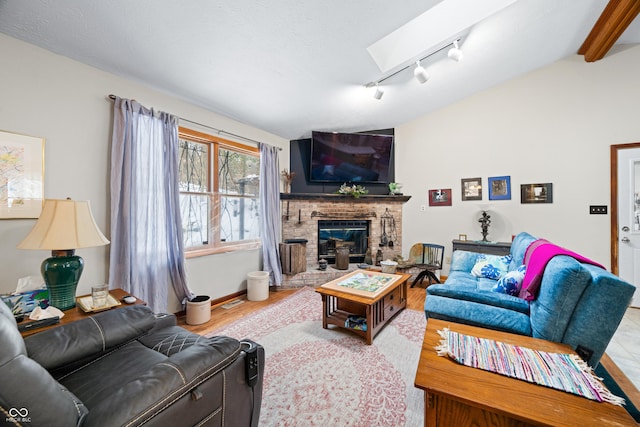 living room featuring light wood finished floors, vaulted ceiling with skylight, and a fireplace