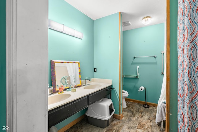 bathroom featuring toilet, a sink, visible vents, baseboards, and double vanity