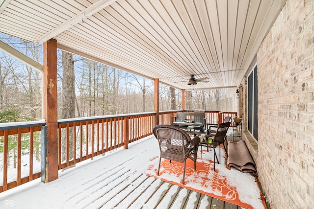 snow covered deck featuring outdoor dining area and a ceiling fan