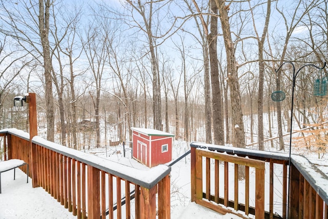 snow covered deck featuring a shed and an outbuilding