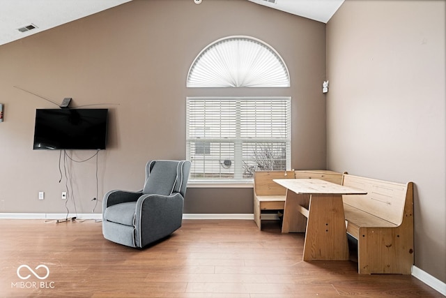 sitting room with vaulted ceiling, wood finished floors, visible vents, and baseboards