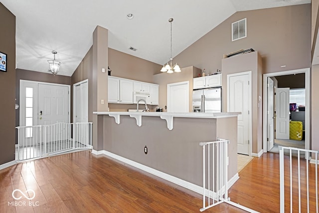 kitchen featuring visible vents, a breakfast bar area, a peninsula, an inviting chandelier, and stainless steel refrigerator with ice dispenser