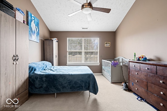 bedroom with a textured ceiling, carpet, visible vents, and a ceiling fan