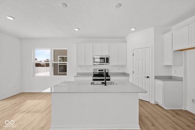 5119 Rolling Meadow Blvd, Indianapolis, IN 46237 - kitchen with light wood-style flooring, stainless steel appliances, white cabinetry, an island with sink, and a sink