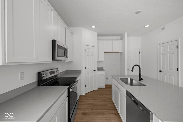 5119 Rolling Meadow Blvd, Indianapolis, IN 46237 - kitchen with stainless steel appliances, a sink, visible vents, white cabinets, and wood finished floors