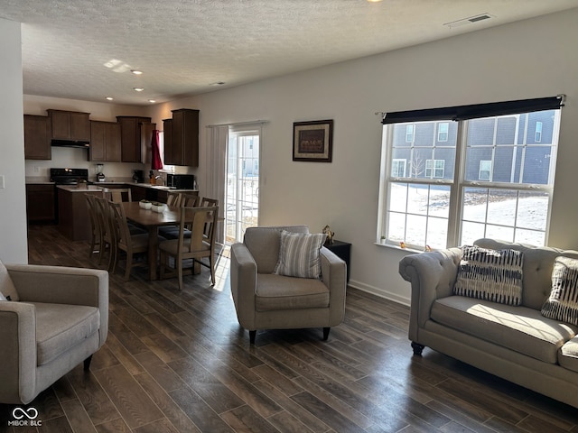 living room with baseboards, visible vents, dark wood finished floors, a textured ceiling, and recessed lighting