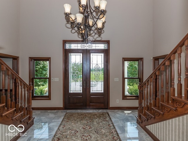 foyer featuring a towering ceiling, baseboards, stairway, and french doors