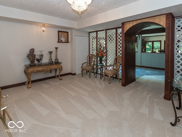 interior space with arched walkways, baseboards, carpet, a textured ceiling, and a notable chandelier