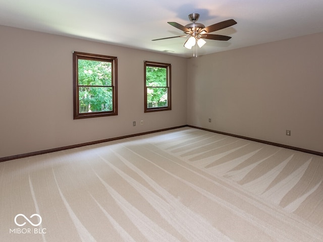 spare room featuring light carpet, ceiling fan, and baseboards