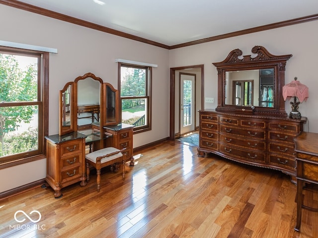 bedroom featuring baseboards, crown molding, and light wood finished floors