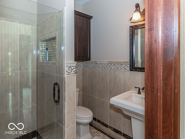 full bathroom with toilet, a wainscoted wall, tile patterned floors, a shower stall, and tile walls