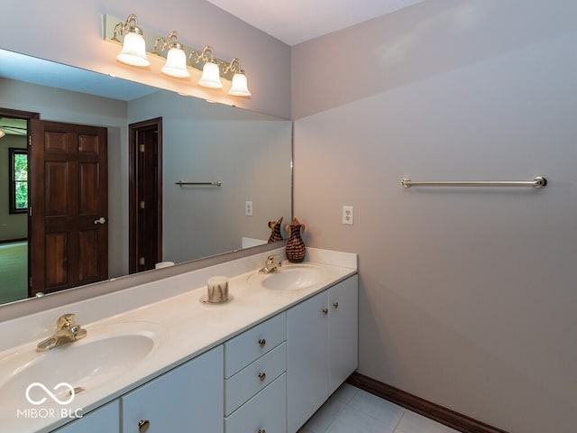 bathroom featuring tile patterned flooring, a sink, baseboards, and double vanity