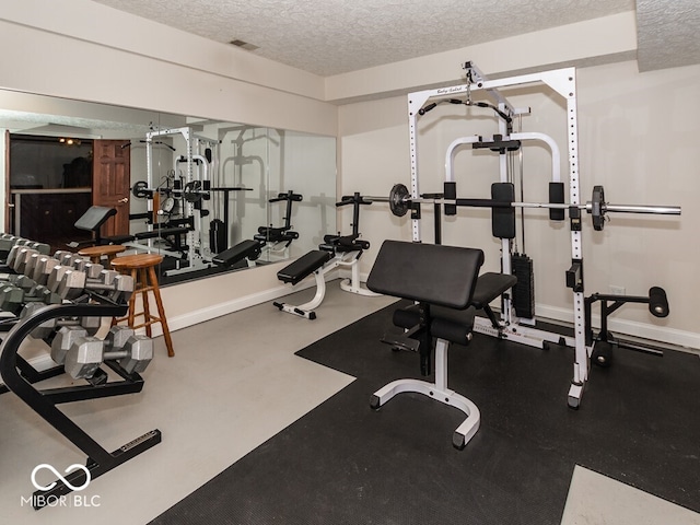 exercise room featuring baseboards, visible vents, and a textured ceiling