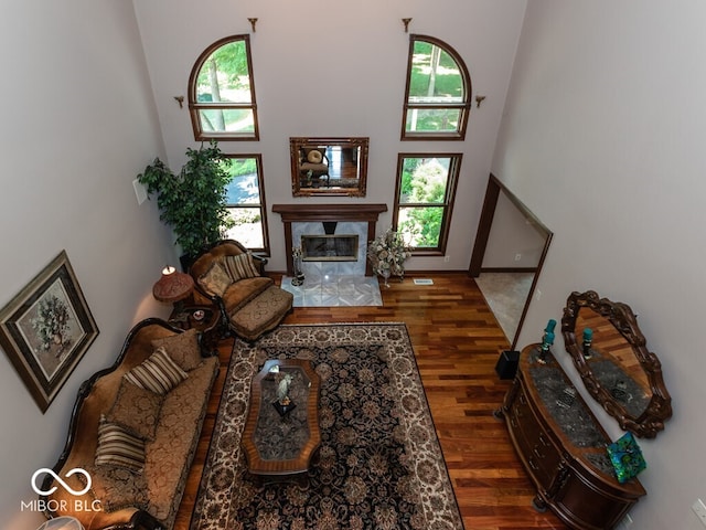 living room featuring a high ceiling, wood finished floors, and a high end fireplace