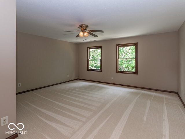 spare room with light carpet, ceiling fan, and baseboards