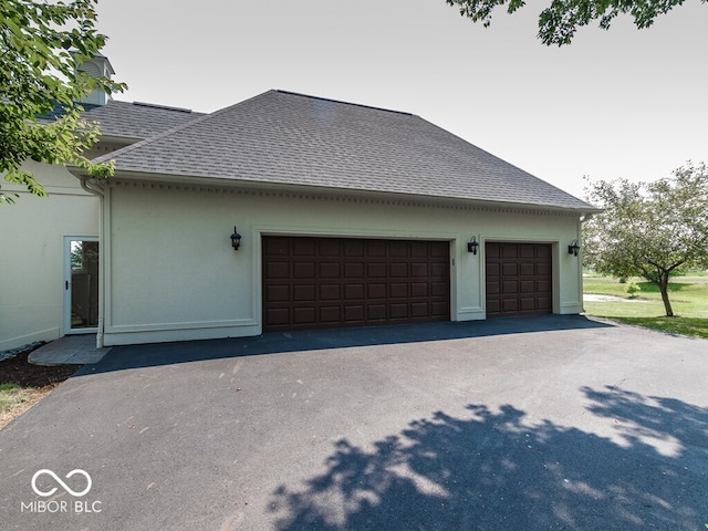 view of side of home featuring aphalt driveway, a shingled roof, and stucco siding