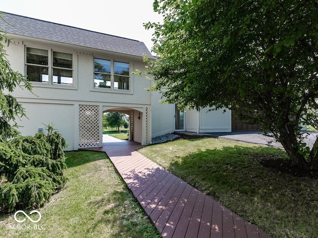 exterior space featuring stucco siding, roof with shingles, and a front yard