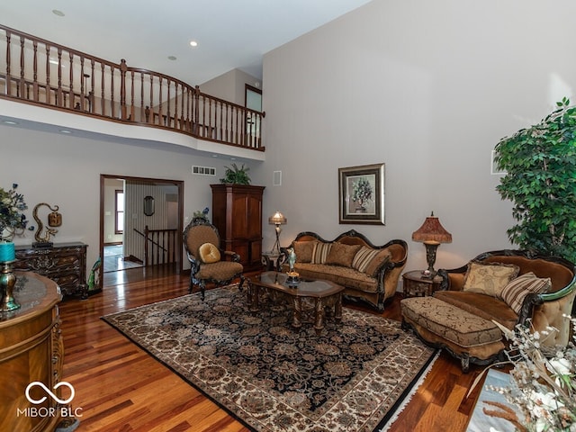 living area featuring a high ceiling, visible vents, and wood finished floors