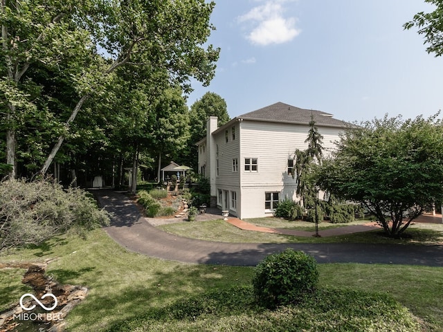 view of side of home with a chimney and a lawn