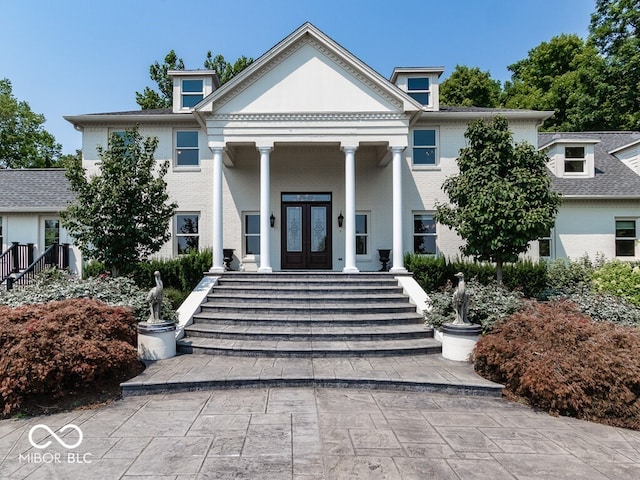 greek revival house with french doors, brick siding, and covered porch