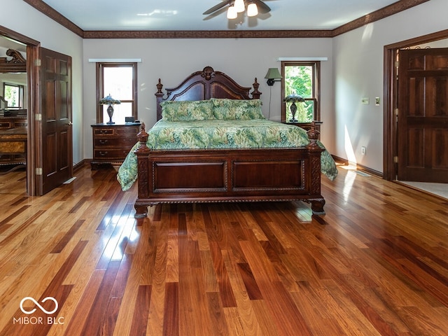 bedroom with multiple windows, crown molding, baseboards, and wood finished floors