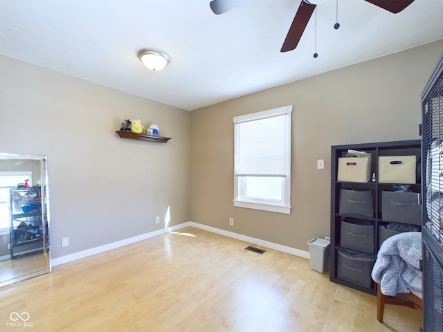 bedroom with a ceiling fan, visible vents, baseboards, and wood finished floors