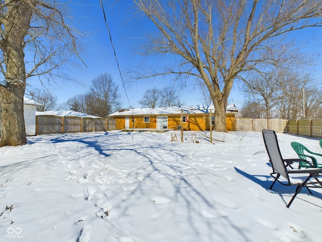 snowy yard featuring a fenced backyard