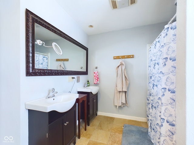 full bathroom with visible vents, baseboards, two vanities, and a sink