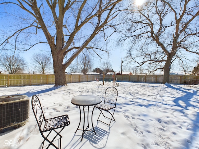 yard covered in snow featuring a fenced backyard and central AC