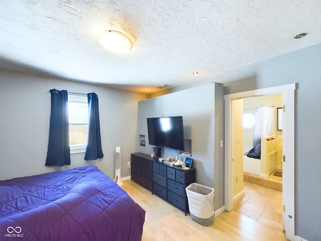 bedroom with light wood-type flooring, visible vents, a textured ceiling, and baseboards