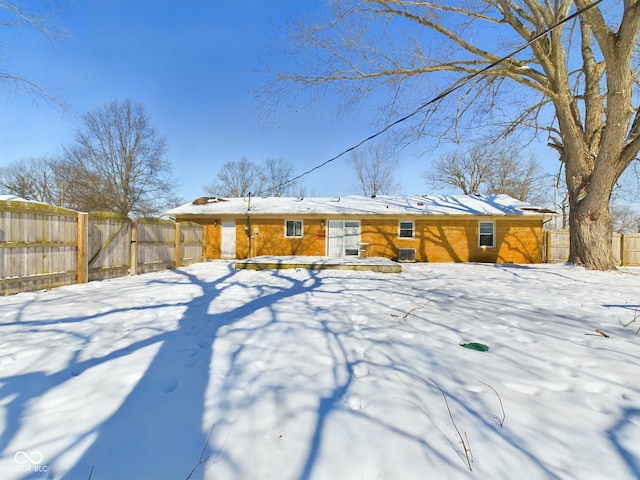 snow covered rear of property with fence