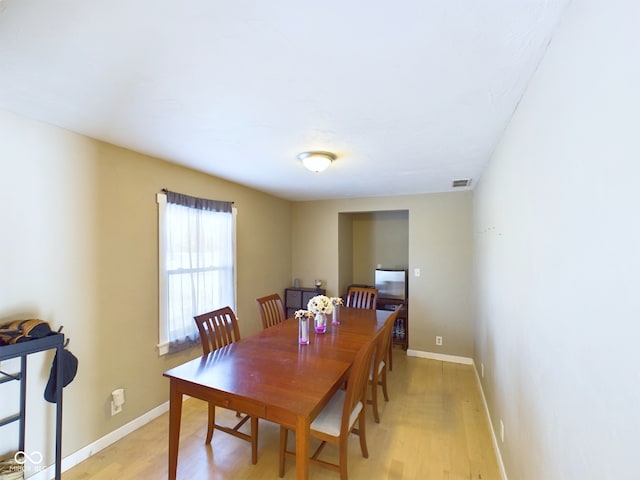 dining area featuring light wood-style floors, baseboards, and visible vents