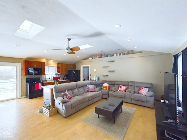 living room with vaulted ceiling with skylight, ceiling fan, light wood finished floors, and recessed lighting