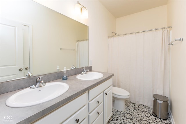 bathroom with double vanity, tile patterned flooring, a sink, and toilet