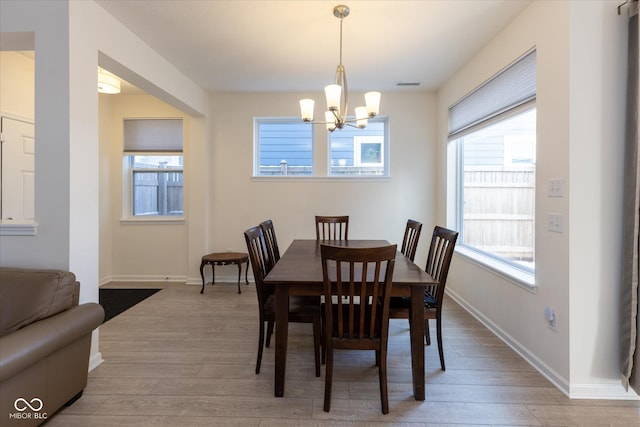 dining area with light wood-type flooring, visible vents, baseboards, and an inviting chandelier