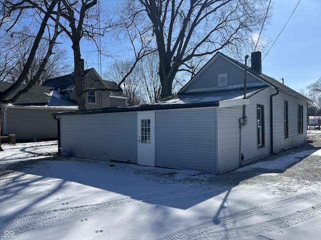 view of snow covered exterior with a chimney