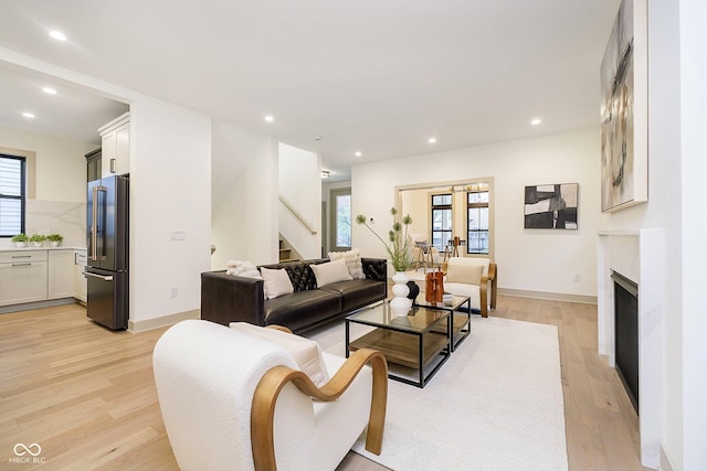 living area featuring stairs, light wood finished floors, a healthy amount of sunlight, and recessed lighting