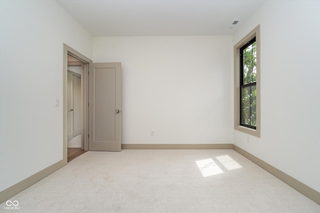 unfurnished room with baseboards and light colored carpet