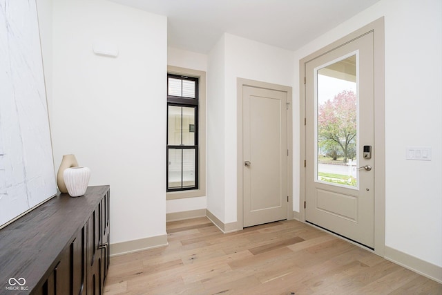 foyer entrance with light wood-style flooring and baseboards